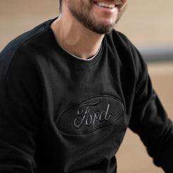 Man wearing a black sweatshirt with 'Ford' logo on a blurred background